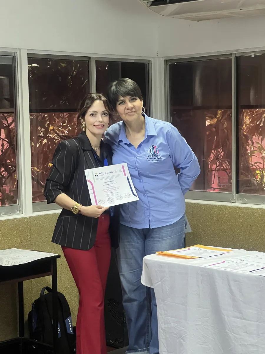 Dos personas sonríen con un certificado del diplomado recién entregado
