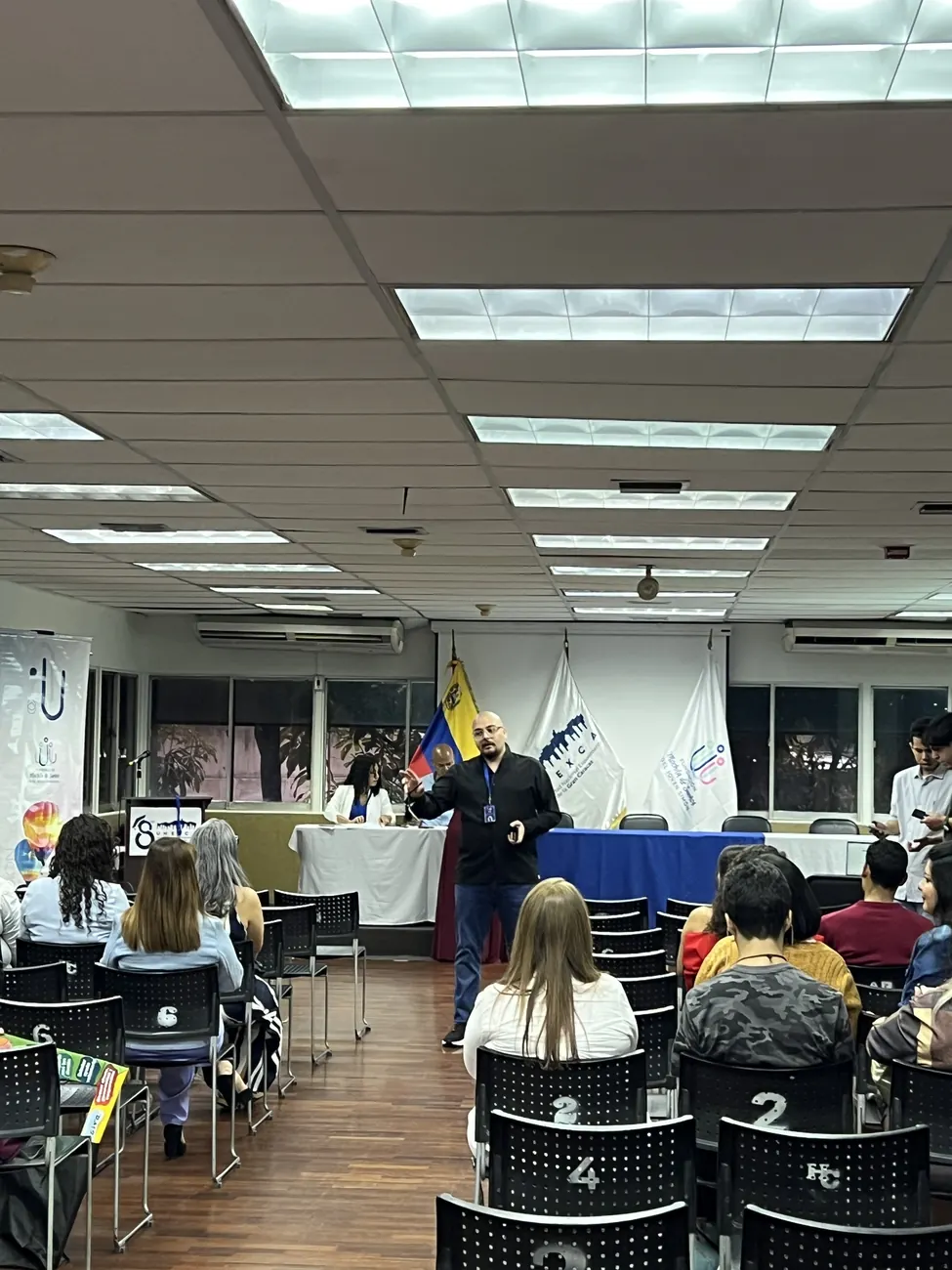 Sesión en un auditorio: participantes sentados y la persona facilitadora frente al grupo